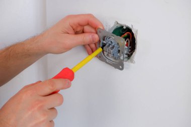 Elektrikçi anahtarı tornavidayla söker. Ellere yakın çekim. Bir elektrikçinin rutin işi. Bağlantıları kontrol ediyorum. Değiştir.