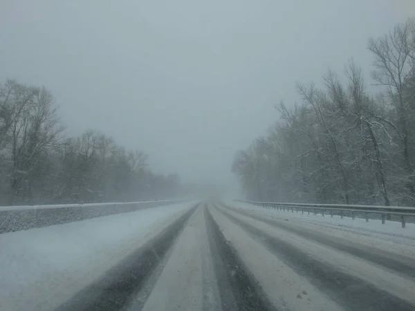 Driving in a snow storm. Poor visibility through the driver\'s glass onto the road covered with snow and ice. Extreme weather in winter. Winter, Blizzard.