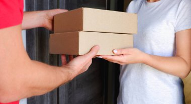 Teslimat servisi. Bir kurye, evinin yakınındaki bir kadına karton kutular dolusu mal verir..