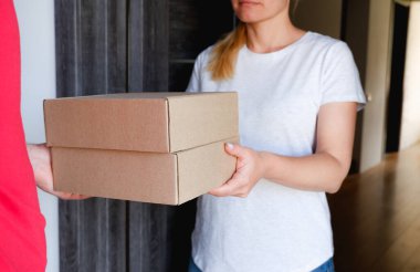 Teslimat servisi. Bir kurye, evinin yakınındaki bir kadına karton kutular dolusu mal verir..