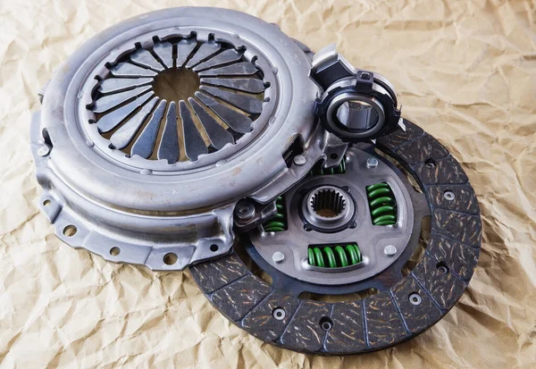 Car spare parts. Car clutch kit. Clutch disc, basket and clutch bearing. Car repair kit clutch manual gearbox on a background of craft paper.