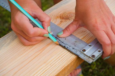 Kadın marangoz tahta bir tahtada kalem izi yapar. ÇEVİR.