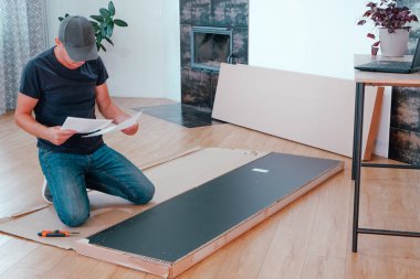 Mobilya montajı iş akışı. Bir adam mağazadan getirilen mobilyaları topluyor. Kabineyi kendin kuruyorsun..