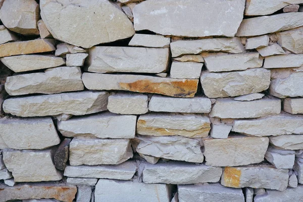 Sandstone masonry texture. Retaining wall lined with sandstone stones. Natural stone background.