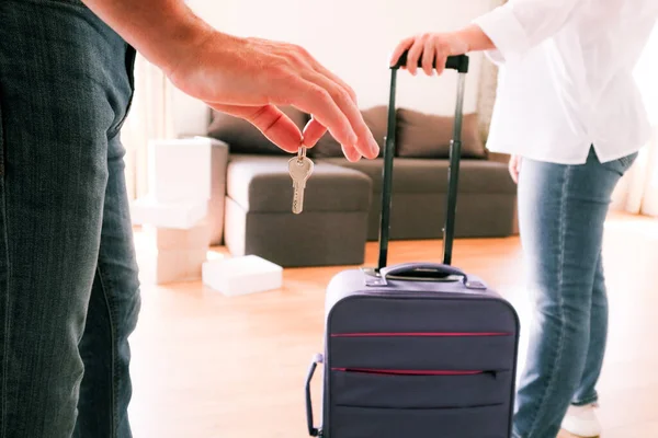 Evin anahtarlarını tutan bir adam ve yeni bir daireye bavul çeken bir kadın. Taşınmak, yeni bir ev kiralamak, emlak, taşınmak ya da birlikte yeni bir hayata başlamak kavramı..