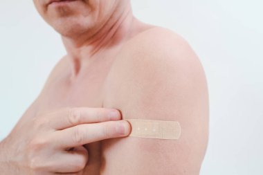 Aşı ya da enjeksiyondan sonra küçük bir bandajla bir adamın üst kolu. Sağlık, aşı ve tıbbi tedavi kavramı.