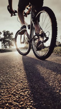Gün batımında şehir yolunda bisiklet süren birinin alçak açılı görüntüsü. Özgürlük kavramı, macera, sağlıklı yaşam tarzı, açık hava sporları ve akşam bisikleti..
