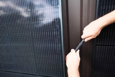 MC4 kablolarını iki güneş paneli arasına bağlayan bir teknisyenin yakın çekimi. Yenilenebilir enerji kavramı, güneş enerjisi kurulumu, temiz teknoloji ve sürdürülebilir elektrik.