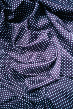 Koyu renkli bir tekstil arka planının tam kare yakın çekimi, küçük, eşit aralıklı, açık mavi ya da mavi benekli, koyu siyah ya da lacivert kumaş yüzeyinde tekrar eden bir desen içerir..