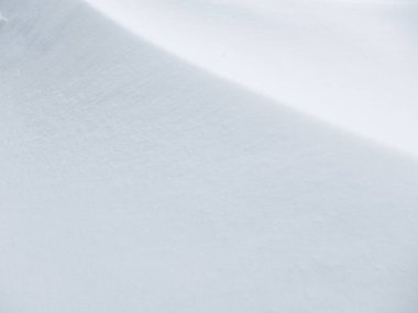 Rüzgarın oluşturduğu hassas çıkıntıları içeren taze ve el değmemiş bir kar yüzeyinin yüksek açılı görüntüsü. Minimalist kış arkaplanı temiz beyaz dokular ve pürüzsüz geçişlerle