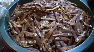 Bir kase dolusu küçük, kurumuş kahverengi balıkla dolu, sıkıca sarılmış, dokusunu detaylıca gösteren bir kase.