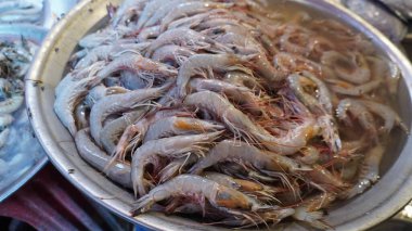 Large silver bowl filled with raw grayish white shrimp