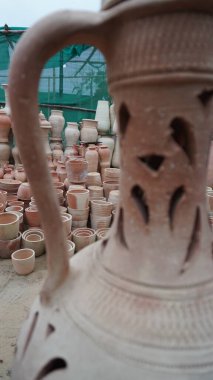 Handle of ornate pitcher framing piles of earthen pots