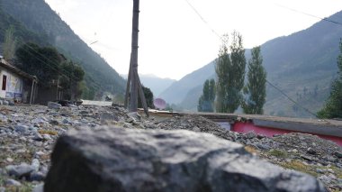 Dağlık kırsal alan kayalık ön planda, köy binaları, sisli tepeler, yerleşim konsepti.