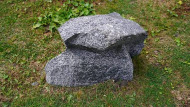 Büyük gri granit kaya, yeşil çimlerde ikiye bölünmüş, sarı yamalı, doğal bir kavram..