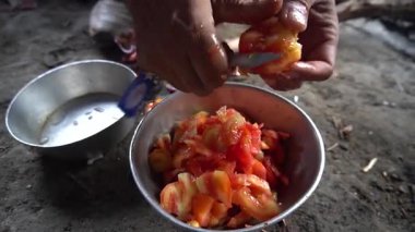 Taşrada metal kasede taze domates doğrayan eller.