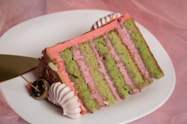 Bir parça pembe sünger keki. Üst manzara, pembe arka planda beyaz tabakta pasta..