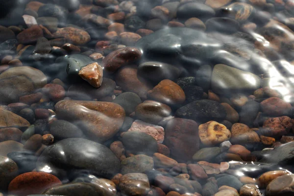 Viele Felsen auf dem Hintergrund des Wassers. Flussufer. Sauberes Wasser. Sauberer Strand zum Entspannen. Umwelt, Ökologie. — Stockfoto