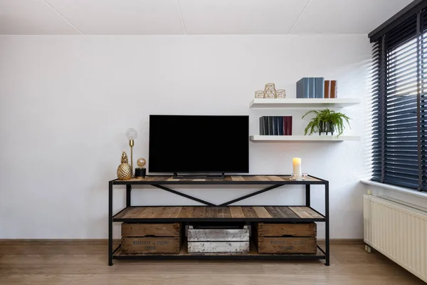 Industrial style living room interior with television on a steel and wood cabinet