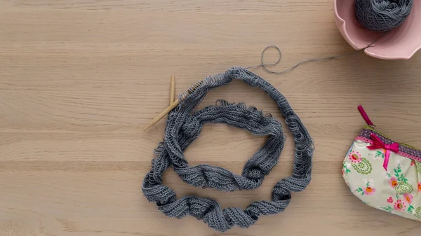 Örgü ipliği ve iğneler bir kase ve çantayla düzdü.