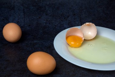 Kırık tavuk yumurtası mavi arka planda bir tabakta