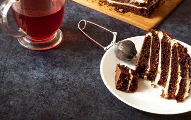 Çay, kahvaltı, çikolatalı pasta ve meyve çayıyla dolu bir tabakta tatlı kek.