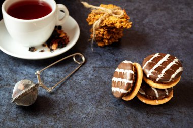 Tatlı kurabiyeler, meyveli çay, çaydanlık, koyu dokulu arka plan, üst manzara