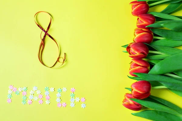 8 Mart, kadınlar günü için kavram, yazıt. Sarı zemin üzerinde 8 Mart, laleler, üst manzara.