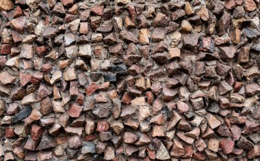 Arkaplanda taşlar, duvarda küçük kaldırım taşları var.