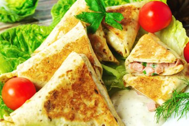 Sosisli ve peynirli kızarmış üçgen tortilla. Beyaz bir tabakta yakın plan, ev yapımı.