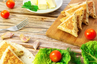 Tahta tahtada yumurta içinde kızarmış peynirli ve sosisli pide, yeşil lahana yapraklı.