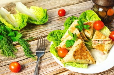 Otlu tortilla ve bir tabakta vişneli domates, genel planda ahşap arka plan, durgun hayat.