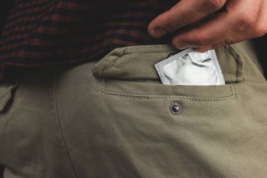 Koyu bir arka planda bir cepteki prezervatifin yakın çekimi.