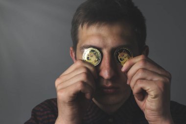 A guy with dogecoin coins in his hands in a close-up in the dark, a glare on the coin clipart
