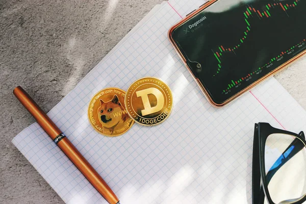 Cep telefonu, diyagramı, ekranda büyüme grafiği olan bir dogecoin, bir dizüstü görünüm dizisinin arka planında