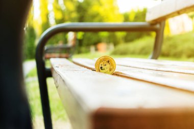 Dogecoin, günbatımının arka planında parkta bir bankta