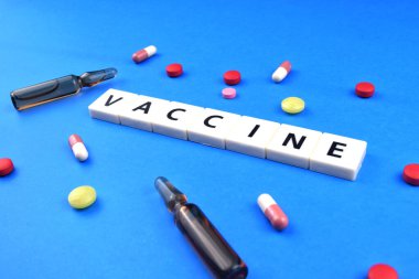 Aşı kelimesi ilaç ve şişeyle mavi zemin üzerinde enjeksiyon için. Tıbbi konsept. Seçici odak resmi.