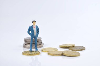 Madeni paraların üzerinde duran minyatür iş adamının seçici odak görüntüsü. İş ve ekonomi kavramı