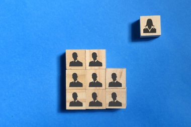 wooden block with men and women icon over a blue background. Gender discrimination concept. Selective focus. clipart