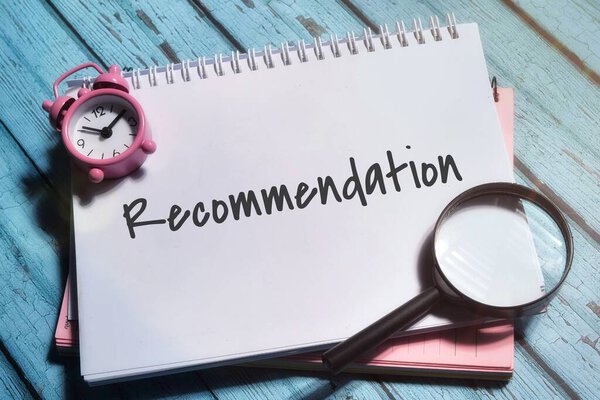 Recommendations wording with magnetic clock,magnifying glass and book over a wooden background