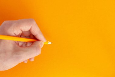 Renkli bir arkaplanda bir kalem tutuyor.