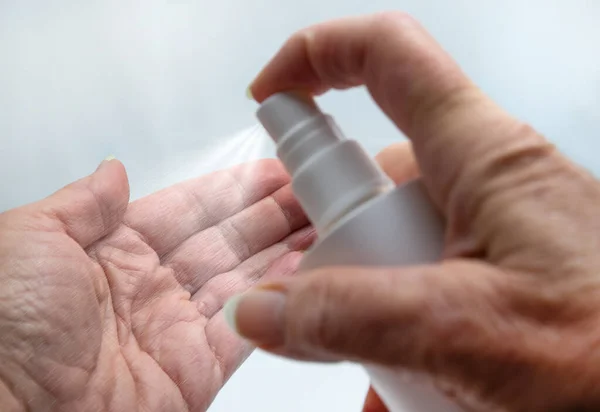 Older woman disinfects hands. Close up.