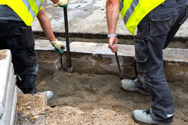Workers replace kerbstones street network. Close up