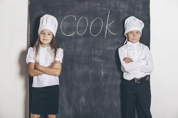Boy and girl cooks with slate Board under the text menu