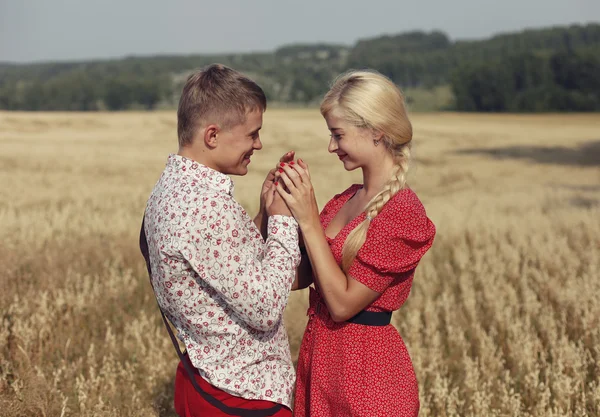 The couple walks through a field of ripe ears of wheat