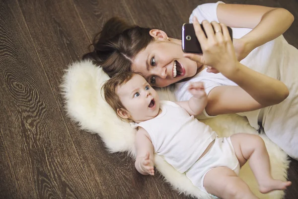 Woman with a baby doing a selfie lying on floor