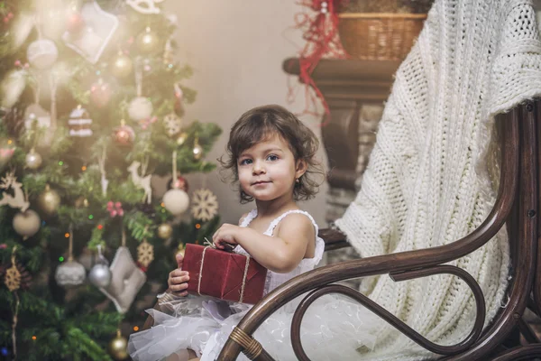 Happy little girl with gifts in the Christmas interior