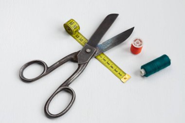 terzi makası, iplik makaraları ve beyaz arkaplanda sarı bir santimetre