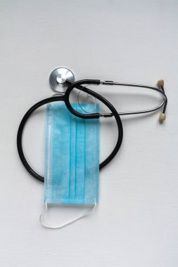 Beyaz arka planda steteskop ve tıbbi maske.