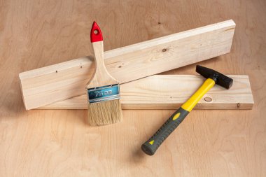Ahşap zemin üzerinde bir boya fırçası ve çekiç.